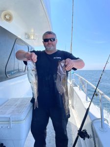 a person holding a fish on a boat posing for the camera