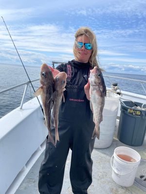 a woman holding a fish on a boat in the water