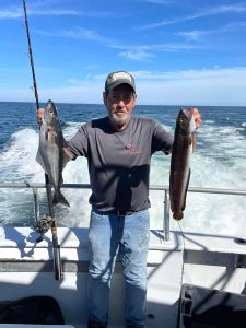 a man holding a fish on a boat in a body of water