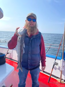 a person holding a fish on a boat in a body of water