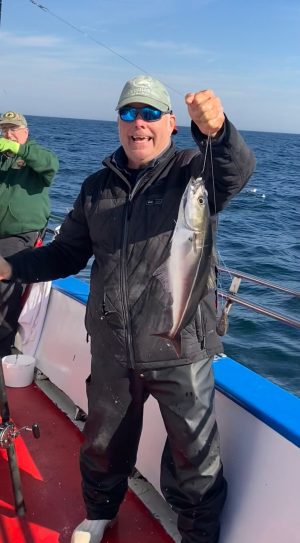 a man holding a fish on a boat in the water