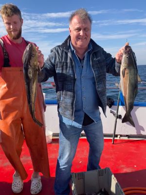a couple of people standing next to a person holding a fish
