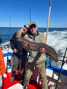 a person holding a fish on a boat posing for the camera