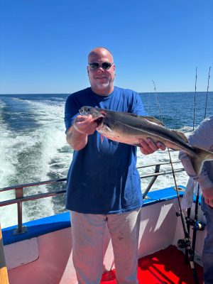 a man holding a fish on a boat in a body of water