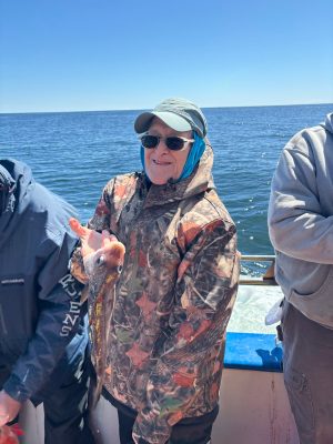 a man holding a fish on a boat in a body of water