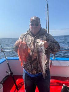a man holding a fish in front of a body of water
