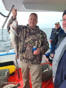 a group of people standing next to a person holding a fish