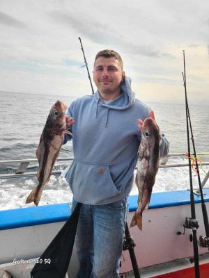 a person holding a fish on a boat in a body of water