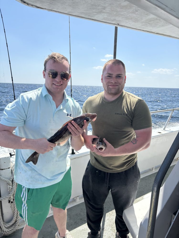 a man and a woman holding a fish on a boat