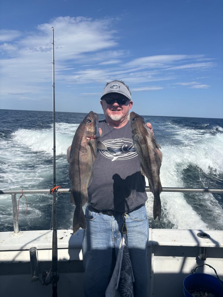 a man holding a fish on a boat in the water