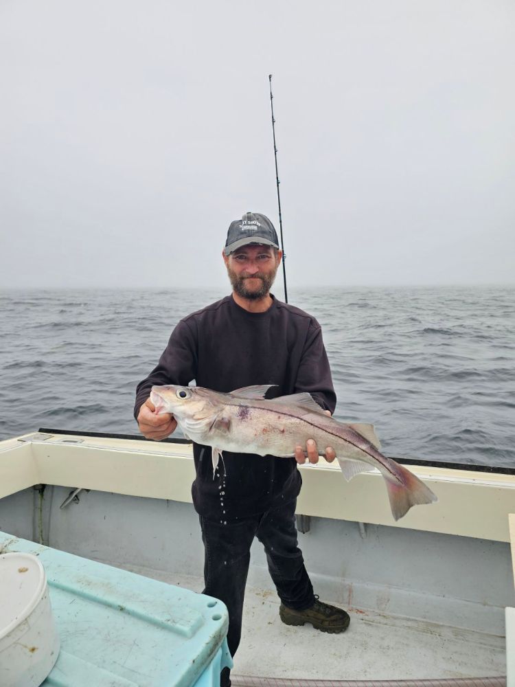 a man holding a fish on a boat in the water