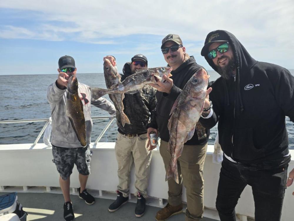 a group of people standing next to a man holding a fish