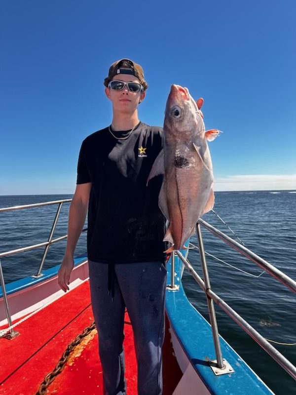 a person holding a fish on a boat in a body of water