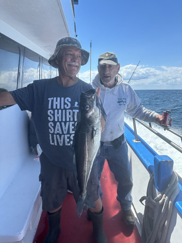 a person holding a fish on a boat posing for the camera