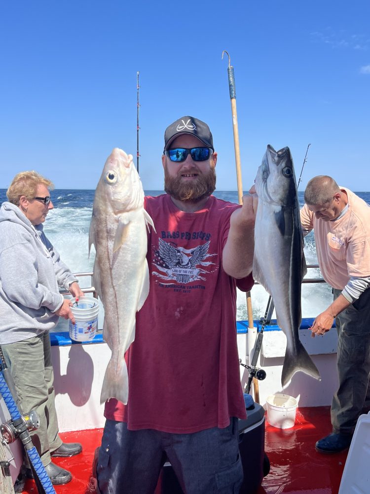 a group of people standing next to a man holding a fish