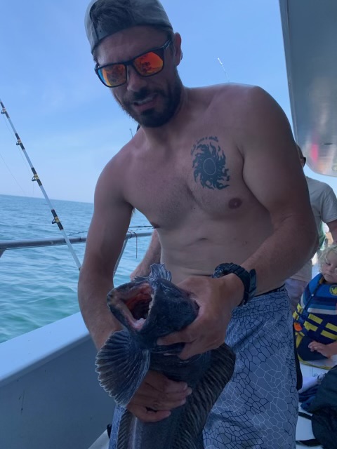 a man holding a fish on a boat in the water