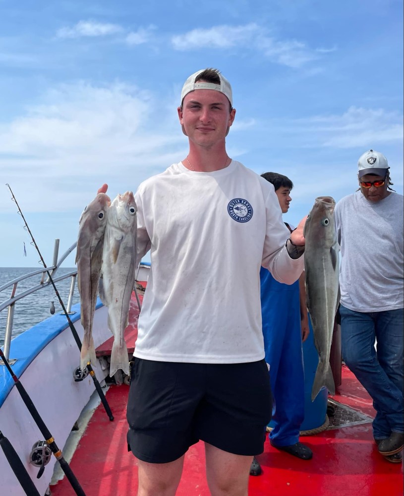 a group of people standing next to a person holding a fish