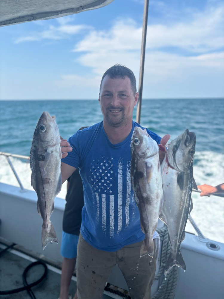 a man holding a fish on a boat in the water