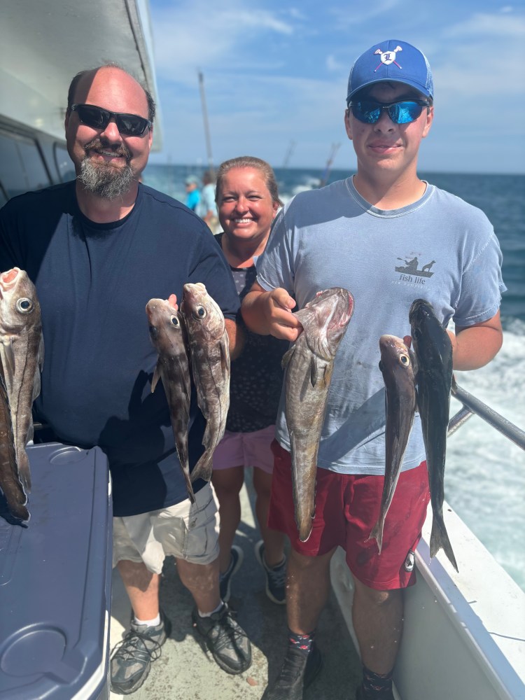 a group of people standing next to a man holding a fish