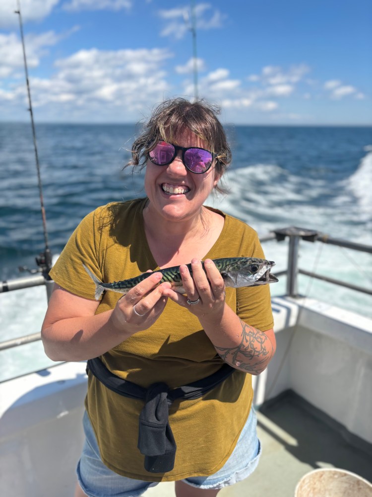 a person holding a fish on a boat in a body of water