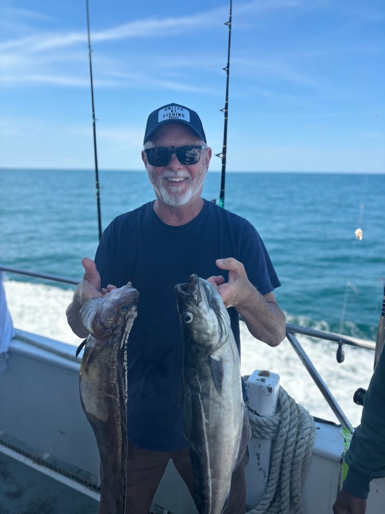 a man holding a fish on a boat in a body of water