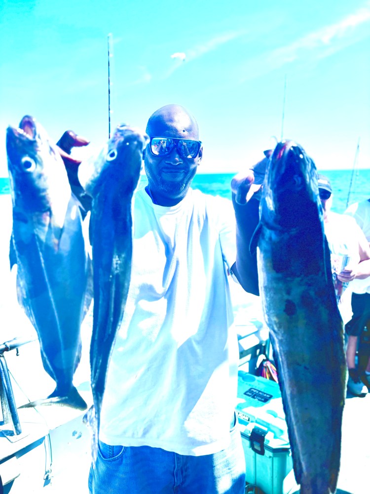 a group of people standing next to a person holding a fish