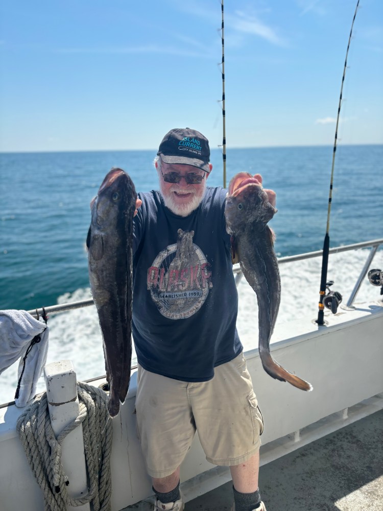 a man holding a fish on a boat in a body of water