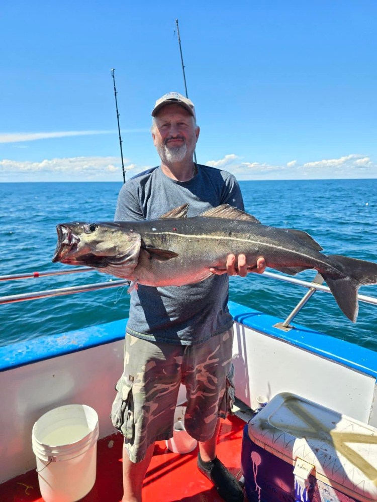 a man holding a fish on a boat in a body of water