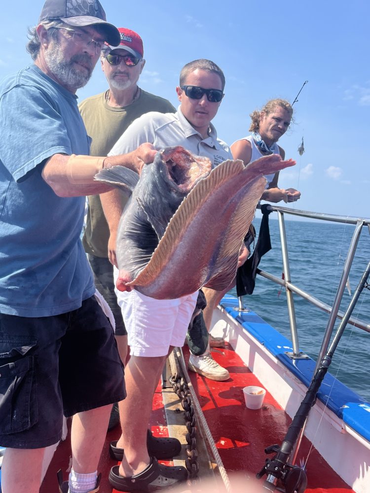 a man holding a fish on a boat in the water