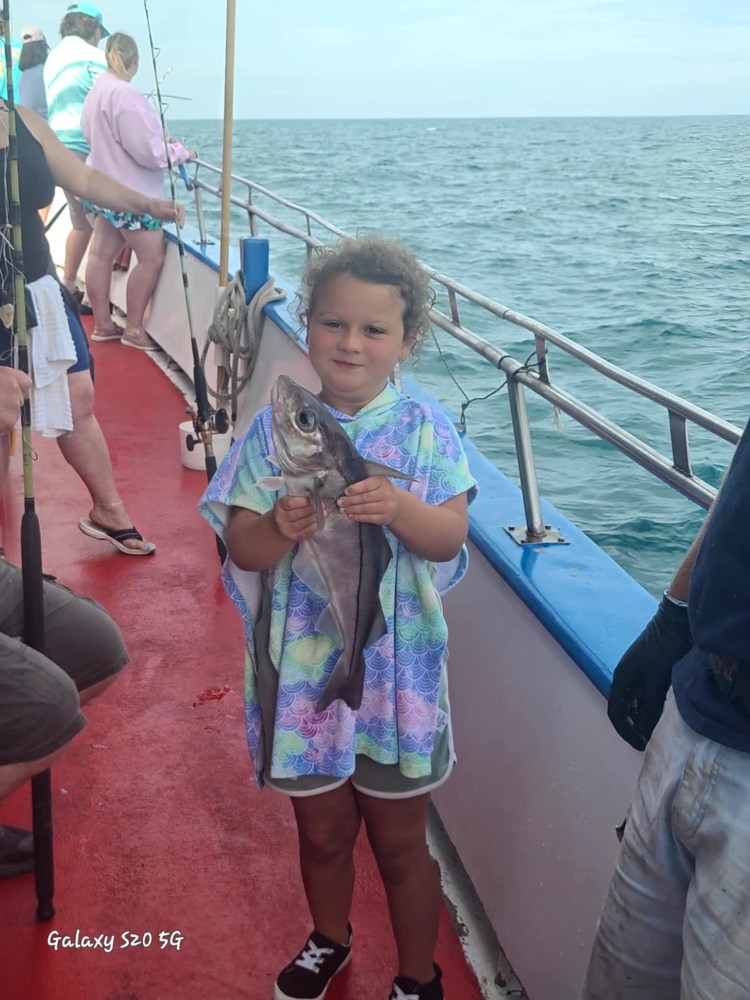 a little boy standing next to a body of water