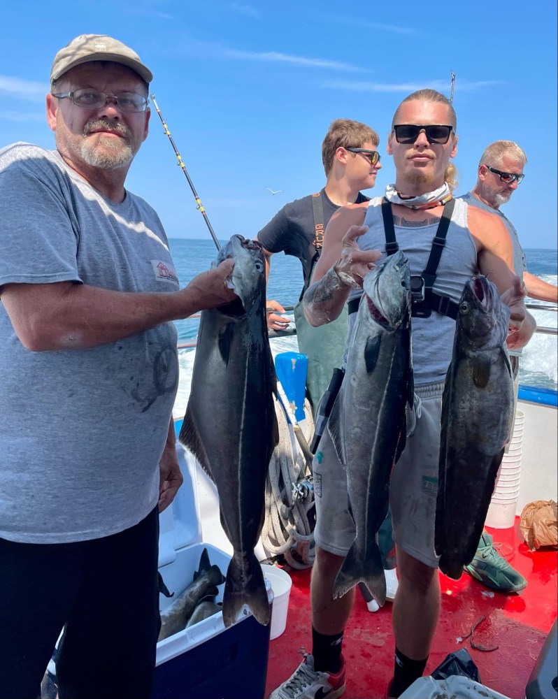 a group of people standing next to a man holding a fish