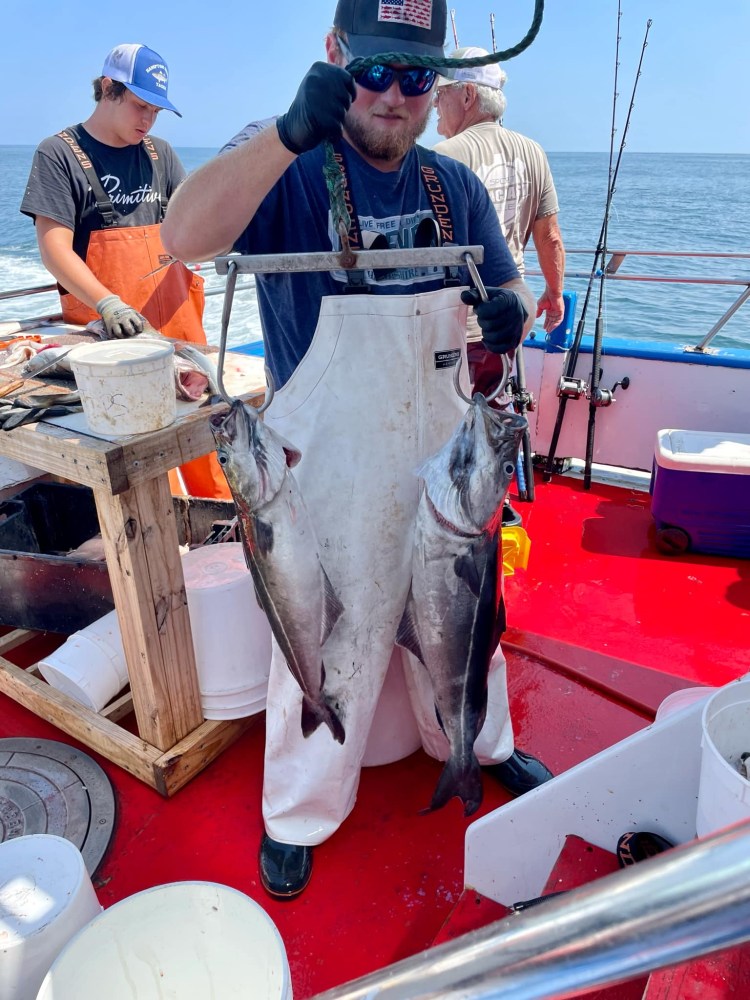 a man holding a fish on a boat