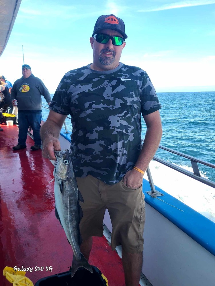 a man holding a fish on a boat in the water