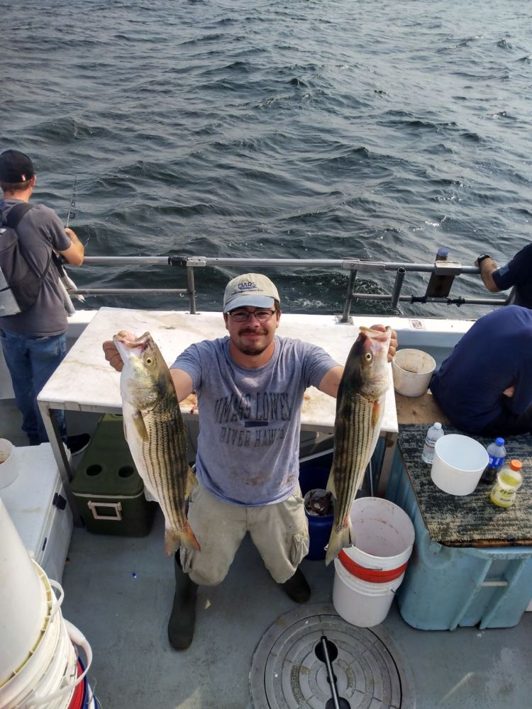 a group of people standing next to a fish on a boat