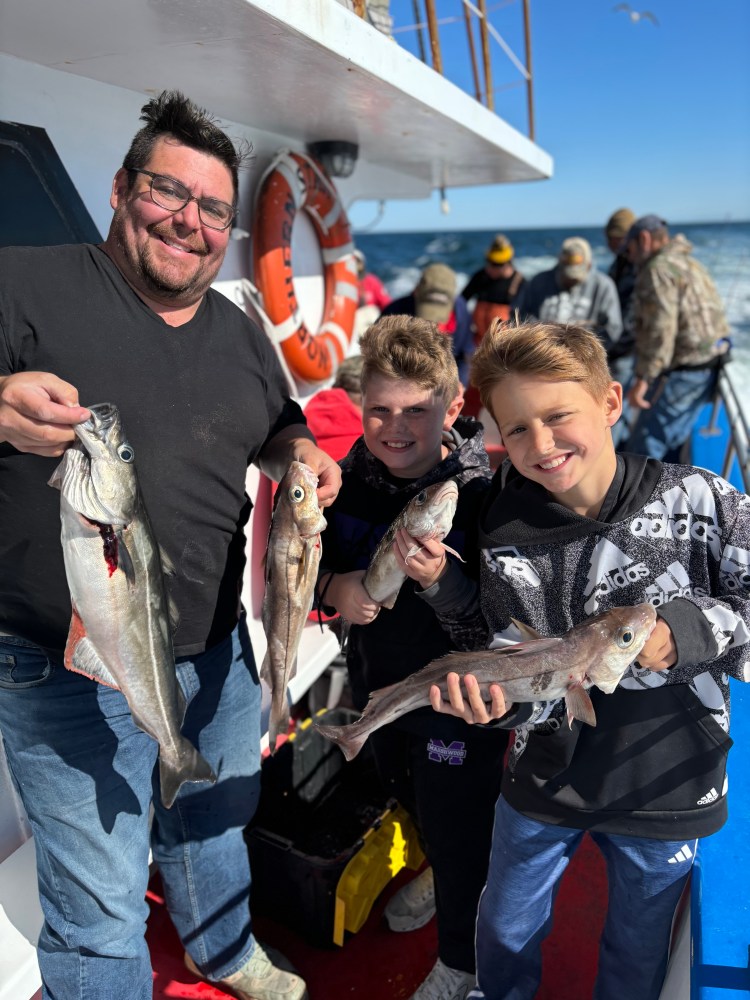 a group of people standing next to a man holding a fish