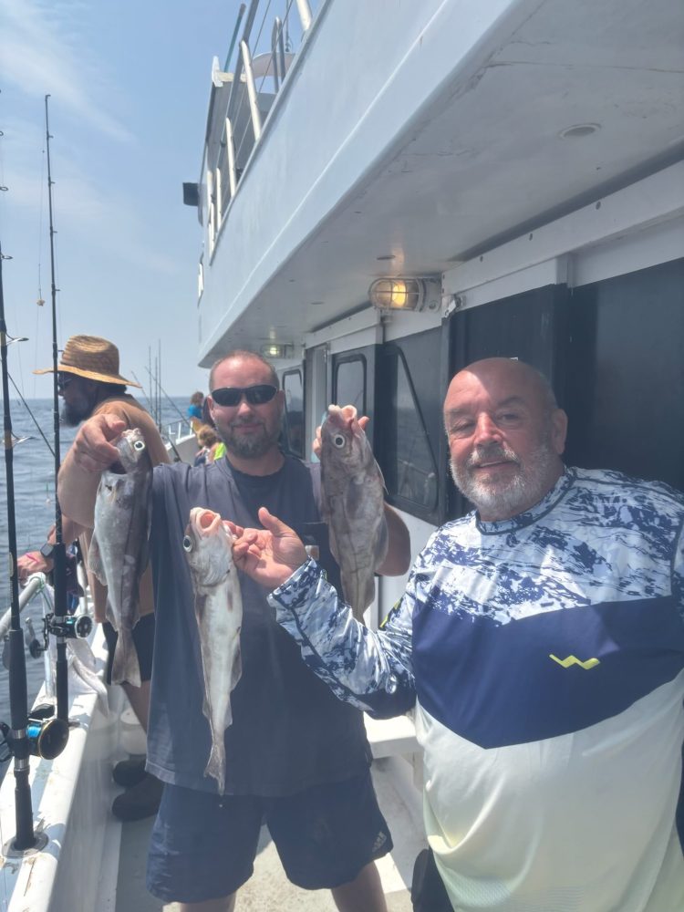 a group of people standing next to a man holding a fish