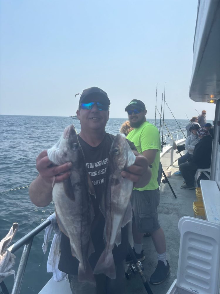 a man holding a fish on a boat in the water