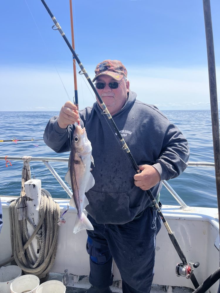 a man holding a fish on a boat in a body of water