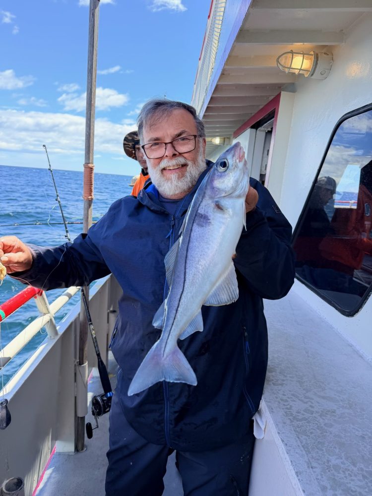 Person holding a large fish on a boat deck.