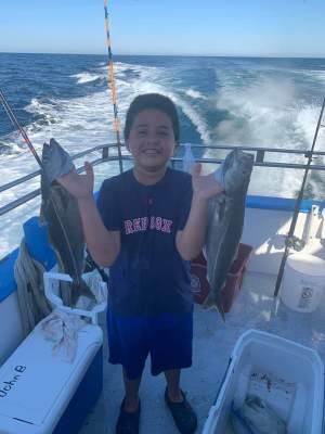 a man standing in front of a boat next to a body of water