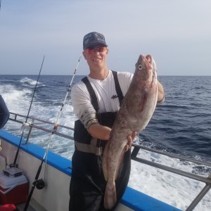 a man holding a fish on a boat in the water