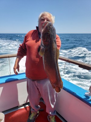a man holding a fish on a boat in a body of water