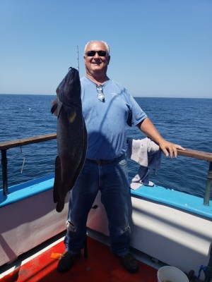 a person holding a fish on a boat in a body of water