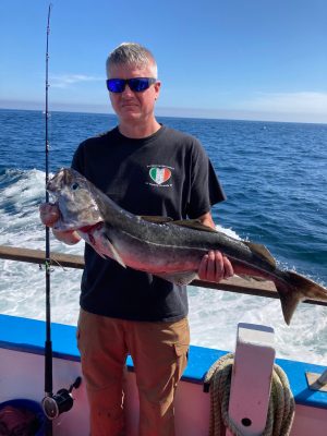 a man holding a fish on a boat in a body of water
