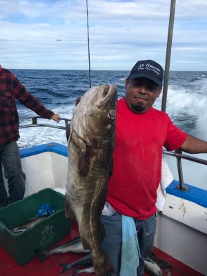 a man holding a fish on a boat in the water