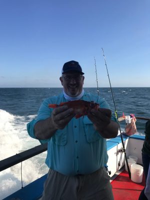 a man holding a fish on a boat in a body of water