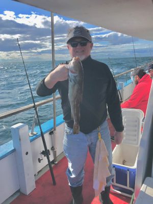 a man holding a fish on a boat posing for the camera