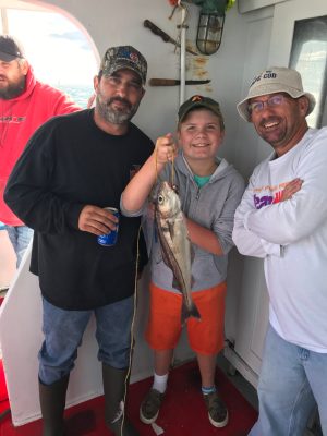 a group of people standing next to a man holding a fish