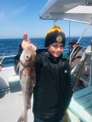 a person holding a fish on a boat in a body of water