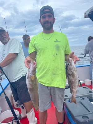 a group of people standing next to a man holding a fish